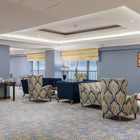 Al Aqeeq Madinah Hotel マディーナ エクステリア 写真 The photo shows a stylish indoor lounge or sitting area. It features several upholstered armchairs arranged around a central space. The chairs have a blue and cream patterned upholstery, creating a sophisticated ambiance. There is a table alongside s