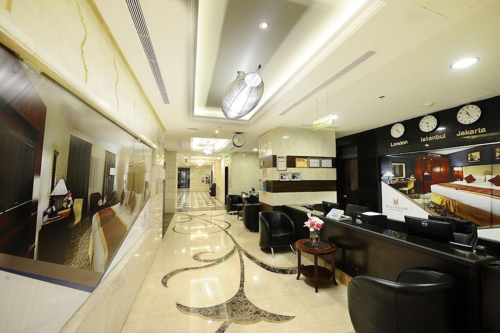 Al Aqeeq Madinah Hotel マディーナ エクステリア 写真 The photo shows the interior of a hotel lobby or reception area. It features a sleek, modern design with elegant marble flooring, decorative lighting fixtures on the ceiling, and a sophisticated color scheme. There are comfortable black seating areas