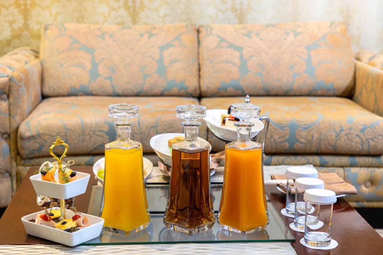 Al Aqeeq Madinah Hotel マディーナ エクステリア 写真 The photo features a beautifully arranged table with several glass decanters filled with liquids. Two decanters, one containing a yellow drink (possibly juice) and another with a darker beverage (possibly tea), are placed prominently. In front of the