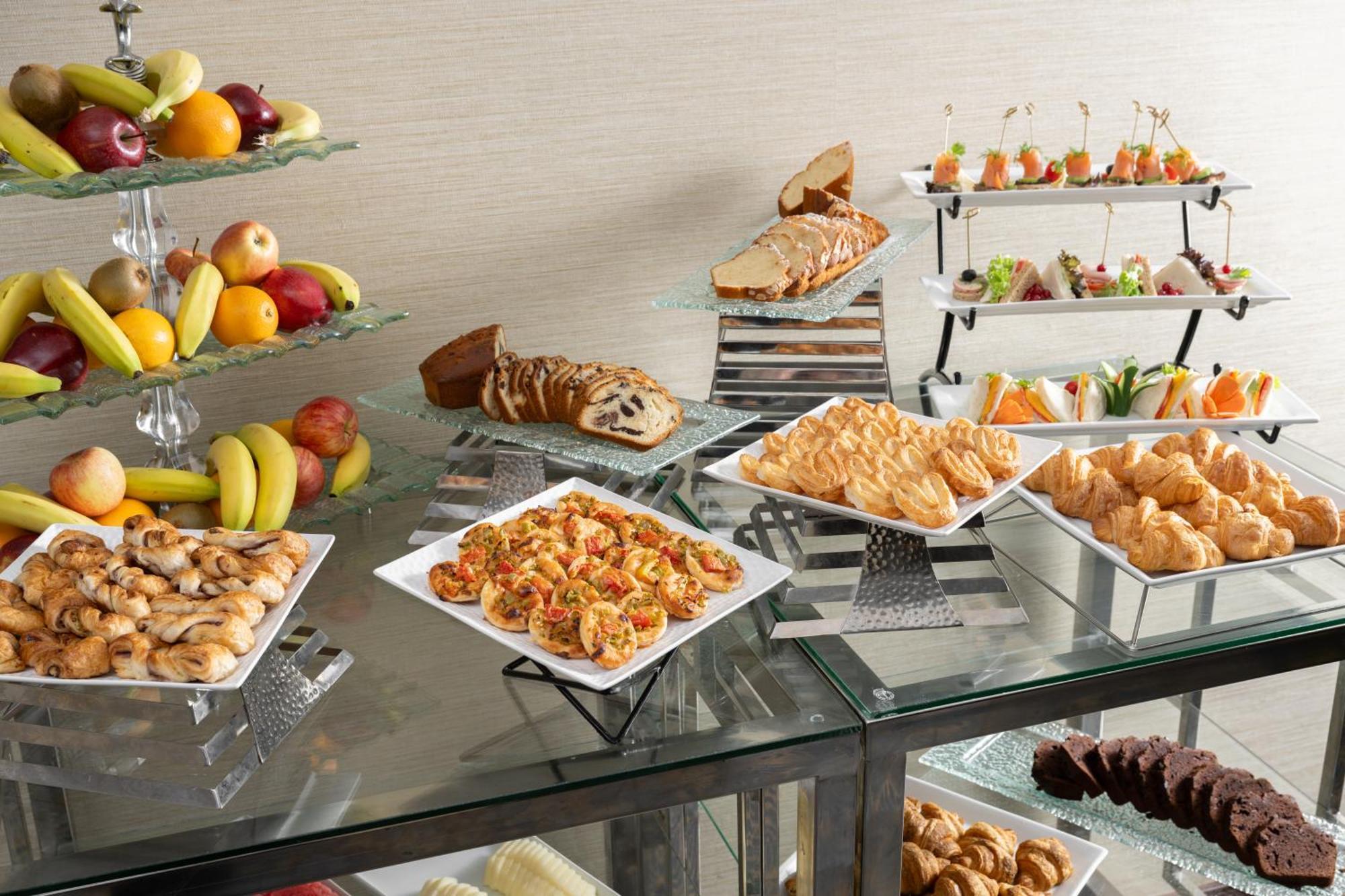 Al Aqeeq Madinah Hotel マディーナ エクステリア 写真 The photo showcases a buffet-style spread featuring a variety of food items. There are several platters with appetizers, including seafood dishes, pastries, and other savory items. In addition, there is a selection of fresh fruit displayed on a glass