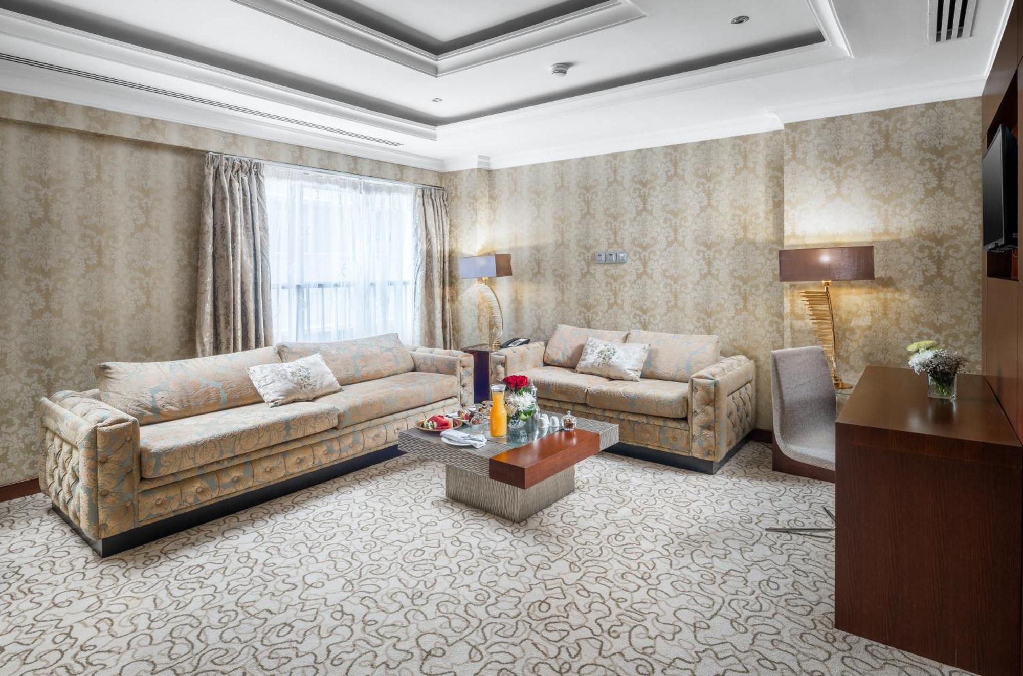 Al Aqeeq Madinah Hotel マディーナ エクステリア 写真 The photo shows a stylish living room with an elegant design. There are two beige sofas placed opposite each other, adorned with decorative pillows. A low coffee table is positioned in the center, featuring various items, possibly drinks or decorativ