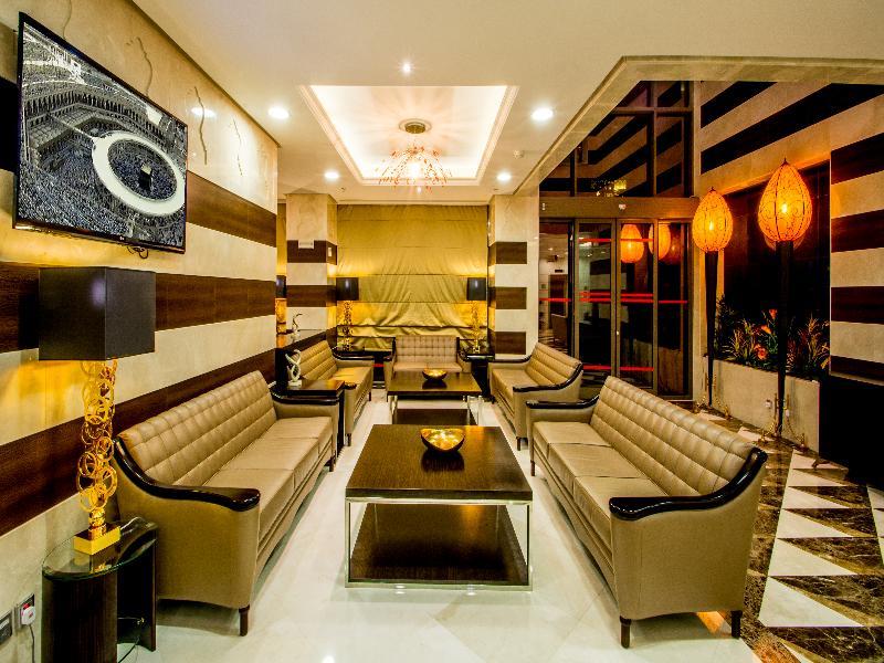 Al Aqeeq Madinah Hotel マディーナ エクステリア 写真 The photo shows a modern and stylish living area or lounge. It features several beige leather sofas arranged around a central black coffee table. The walls are decorated with a mix of light colors and dark wooden accents. There is a large flat-screen