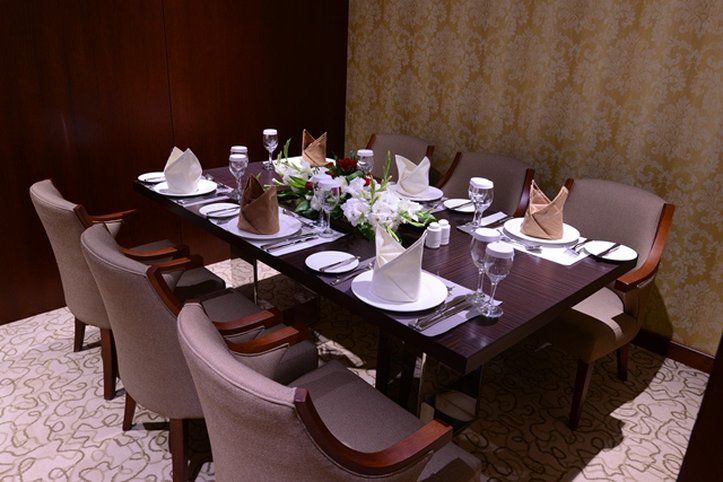 Al Aqeeq Madinah Hotel マディーナ エクステリア 写真 The photo shows an elegantly arranged dining table set for a formal meal. The table is rectangular and made of dark wood. It is adorned with white plates, glassware, and neatly folded napkins placed on top of each plate. The napkins are in two colors